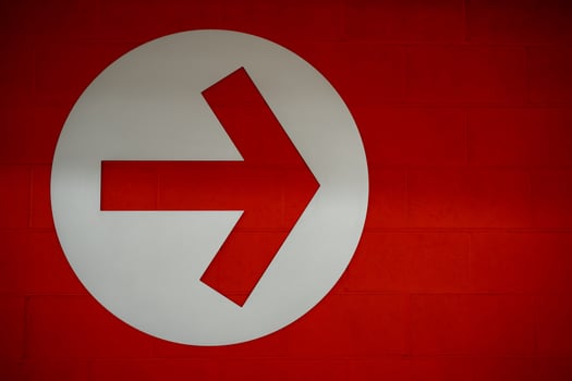 Arrow sign in white circle on red brick wall background, Directional Arrow  pointing to right side photo