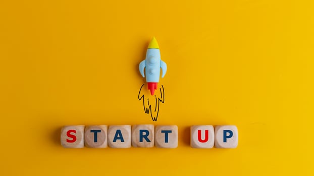Start up concept. A symbol of a quick start of a new project in business. Rocket and cubes with text Start up on a yellow background. photo