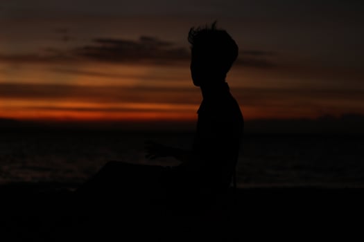 Silhouette of a young man standing by the lake enjoying the sunset. peaceful atmosphere in nature photo