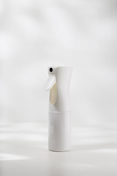 White alcohol spray bottle on a white wooden table. photo