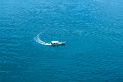 Fishing boat traveling in the beautiful blue sea. Fishing boat spinning photo