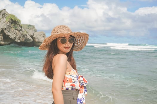 A happy young Asian woman wearing beach hat is posing to the camera at the beach in Gunungkidul, Indonesia photo