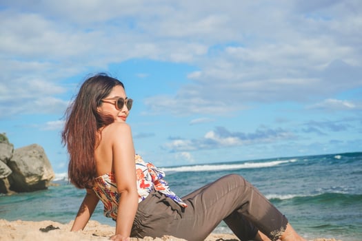 Young Asian woman sit on the beach sand. Portrait sexy Asian lady traveling and relaxing in the summer with tropical nature. photo
