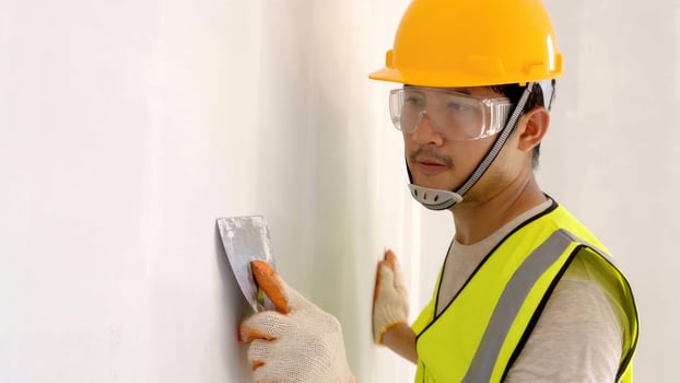 Asian construction worker,spatula in hand against the background of a white wall, work plasterer. Putty walls with their own hands. photo