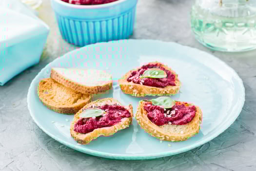 Homemade bruschetta with beetroot hummus on small baked baguette toast on a plate on the table photo