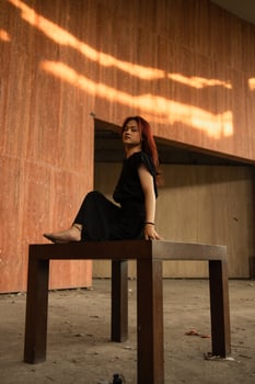 an Asian man with long hair is sitting and posing on a brown table photo