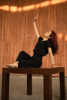 an Asian man with long hair is sitting and posing on a brown table photo
