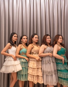 a group of Asian women are standing in front of the curtains of a luxury hotel while wearing dresses at a party photo
