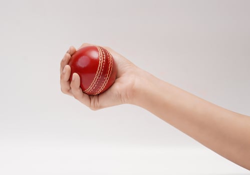 A Female Hand Holding A Red Test Match Leather Stitch Cricket Ball Closeup Picture White Background photo