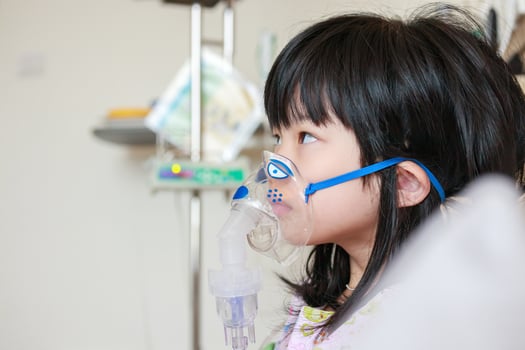 Sick little asian girl inhalation with nebulizer for respiratory treatment photo