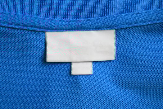 Blank white laundry care clothes label on blue shirt fabric texture background photo