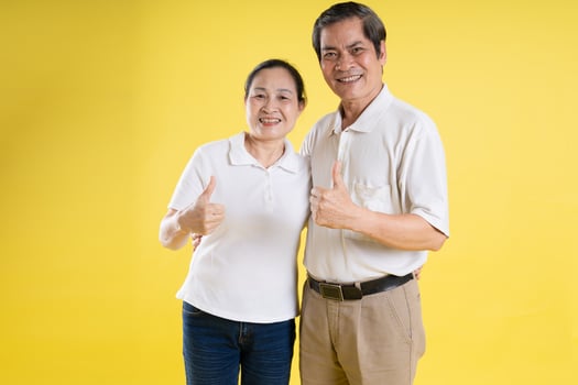 portrait of middle aged asian couple posing on yellow background photo