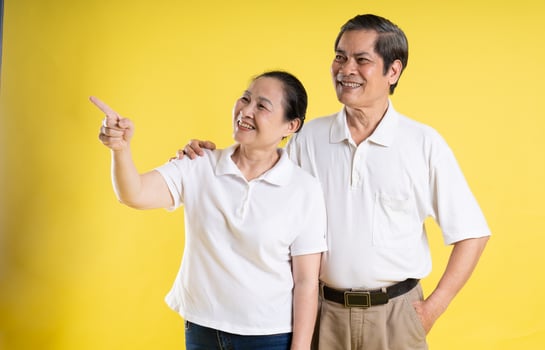portrait of middle aged asian couple posing on yellow background photo