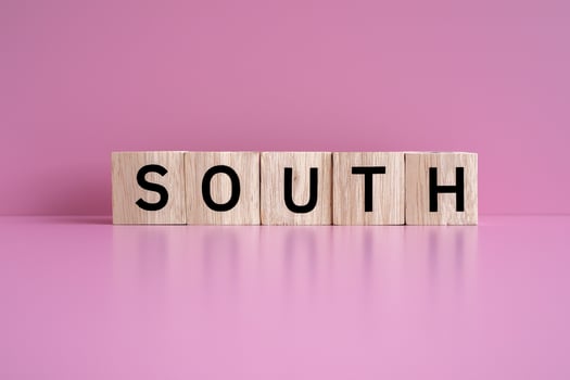 Wooden blocks form the text SOUTH against a pink background. photo