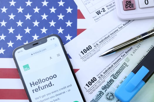 KHARKOV, UKRAINE - MARCH 5, 2021 HR Block website on iPhone 12 pro screen with 1040 and w-2 paper tax forms on US flag photo