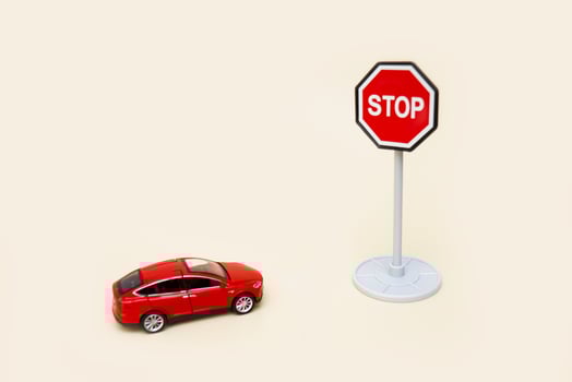 toy red car in front of a stop sign on a light background with copy space photo