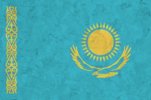 Kazakhstan flag depicted in bright paint colors on old relief plastering wall. Textured banner on rough background photo