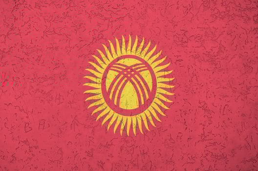 Kyrgyzstan flag depicted in bright paint colors on old relief plastering wall. Textured banner on rough background photo