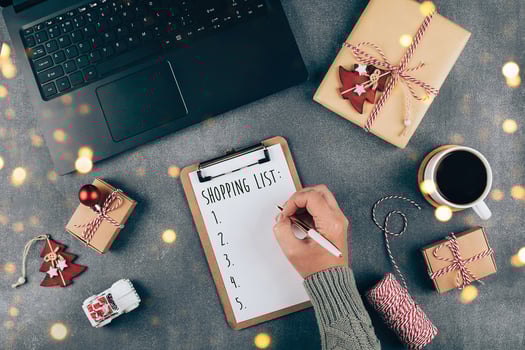 Christmas online shopping flat lay. Girl writing shopping list. Laptop, present box, cup of coffee photo