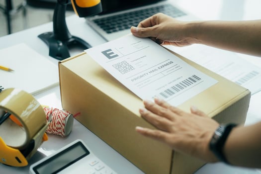 Young business owner putting shipping label on parcel. photo