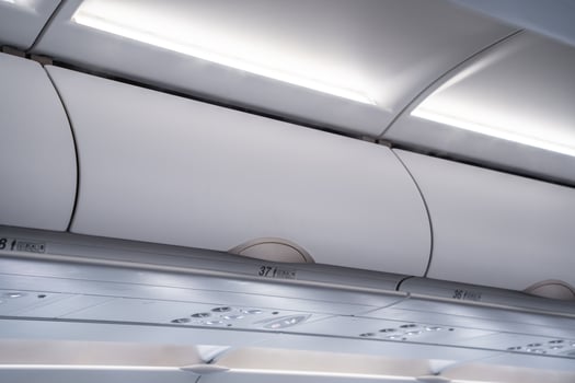 carry on luggage is stowed in overhead bins on a crowded airplane photo