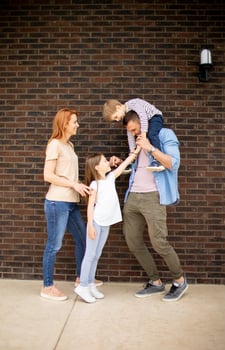 Family with a mother, father, son and daughter standing by the wall of brick house photo