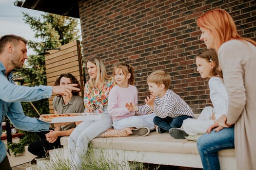 Group of young people and kids eating pizza in the house backyard photo