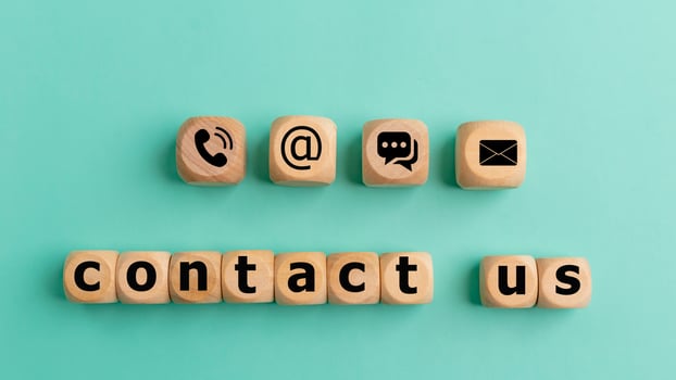 Contact us text on wooden cubes on a blue background. Wooden cube symbol telephone, mail, address, and mobile phone. Website page contact us or e-mail marketing concept. photo
