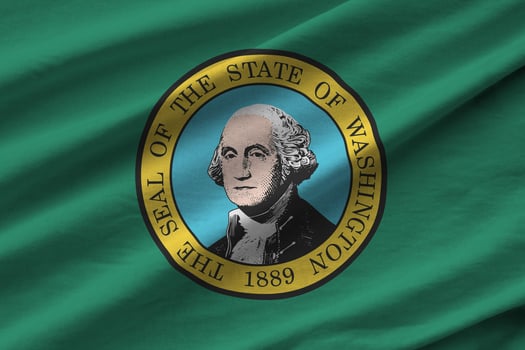 Washington US state flag with big folds waving close up under the studio light indoors. The official symbols and colors in banner photo