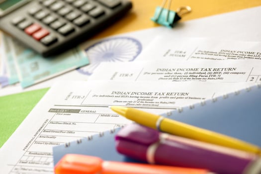 KYIV, UKRAINE - MAY 4, 2022 Indian income tax return blank form with pen and indian rupees bills photo