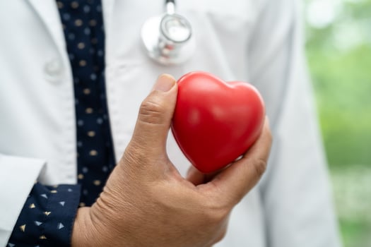 Doctor holding a red heart in hospital ward, healthy strong medical concept. photo