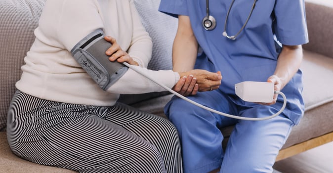 Homecare nursing service and elderly people cardiology healthcare. Close up of young hispanic female doctor nurse check mature caucasian man patient heartbeat using stethoscope during visit photo