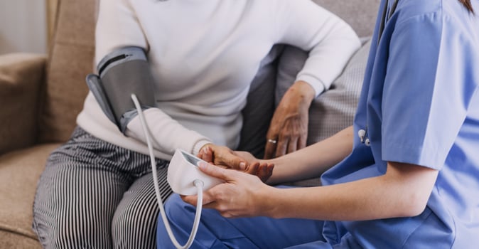 Homecare nursing service and elderly people cardiology healthcare. Close up of young hispanic female doctor nurse check mature caucasian man patient heartbeat using stethoscope during visit photo