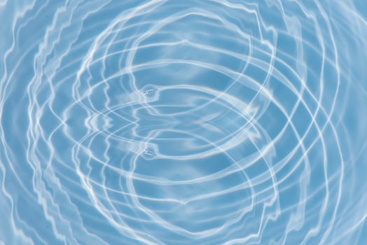 Blue water with ripples on the surface. Defocus blurred transparent blue colored clear calm water surface texture with splashes and bubbles. Water waves with shining pattern texture background. photo