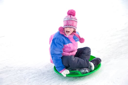 A girl in a winter jacket screaming moves down from a snow slide photo
