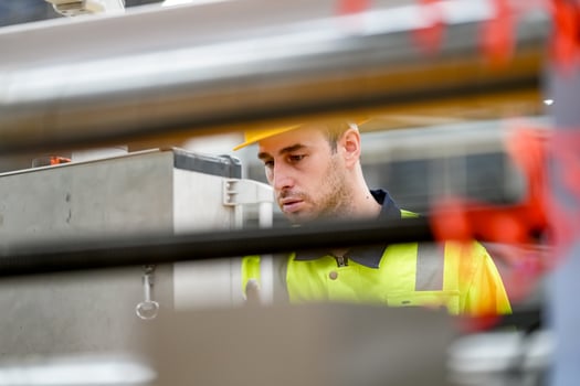 A man in a safety vest looking at a machine photo