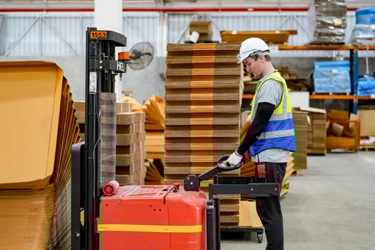A man is standing next to a forklift in a warehouse photo