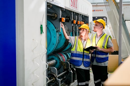 Two people in safety vests looking at a machine photo