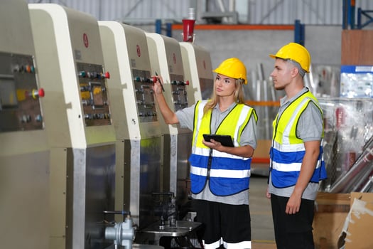 Two workers in safety vests standing next to a machine photo