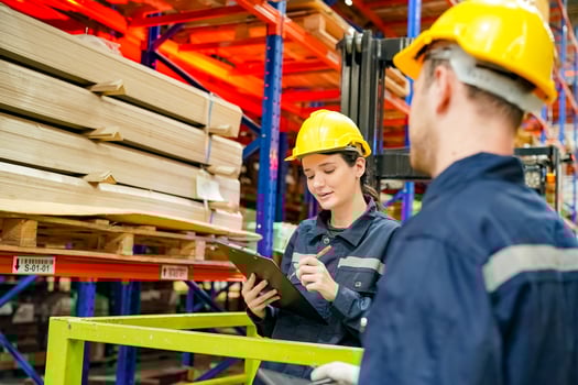 Two workers in a warehouse looking at a clipboard photo
