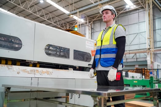 A man in a safety vest standing in front of a machine photo