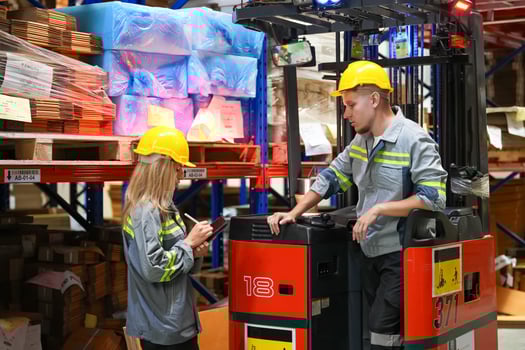 Two people working on a forklift in a warehouse photo