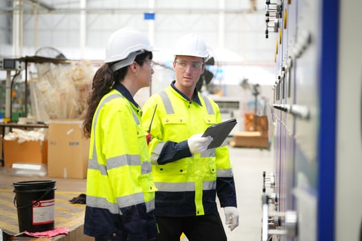 Two workers in safety gear looking at a tablet photo