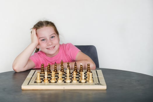 smiling girl in front of chess set out for play photo