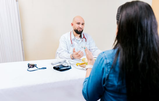 Back view of a female patient talking to the nutritionist. Smiling nutritionist explaining to a female patient, Nutritionist man talking to woman patient in office photo