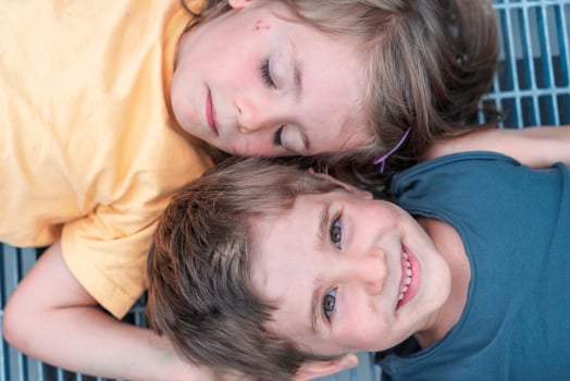 portrait of twins boys and girls lying on a metal grate photo