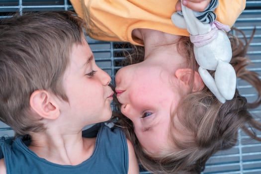 portrait of twins male and female are kissing lying on a metal grate photo