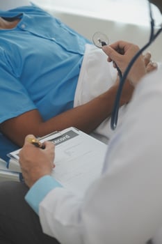 Close up of doctor sitting on bedside of male patient in hospital photo
