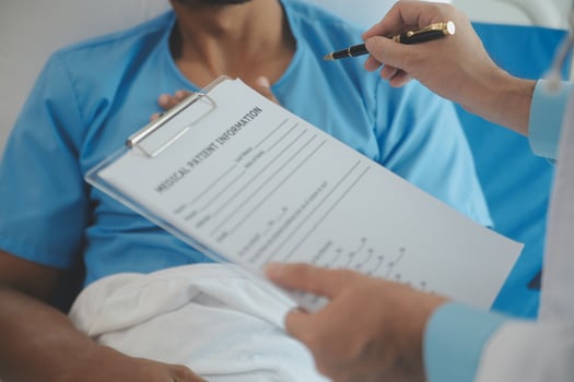 Close up of doctor sitting on bedside of male patient in hospital photo
