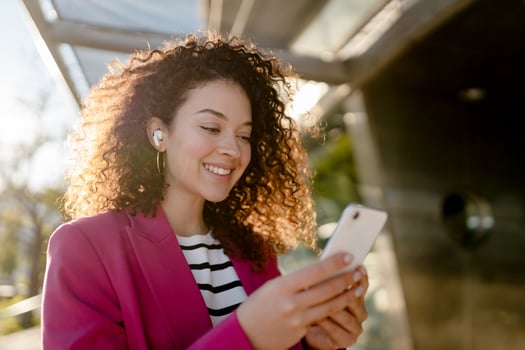pretty curly woman in city street in stylish pink jacket, student education photo